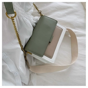 Detail of color-block crossbody bag with gold chain and wide woven strap on fabric