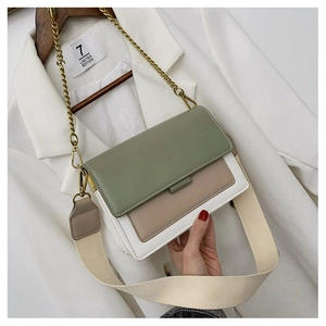 Detail of color-block crossbody bag with wide canvas strap and metal chain on blazer