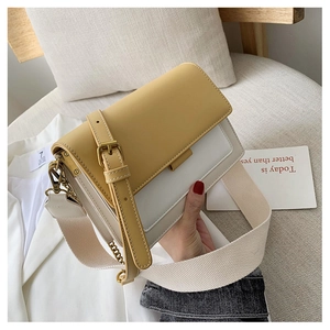 Close-up of color-block crossbody bag with wide fabric strap and gold hardware accents
