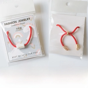Detail view of red braided Libra zodiac bracelet on white display card packaging