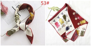 Close-up of a square silk scarf with deep red cartoon patterns and beige background