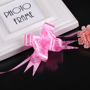 Close-up of pink pull bow ribbon with white rose pattern for gift wrapping and party decor