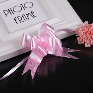 Detailed view of a pink satin gift bow with heart patterns on a reflective surface
