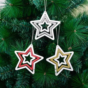 Three hollow star Christmas ornaments in gold, silver, and red hanging on pine branches