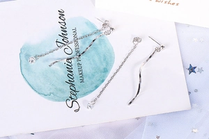 Close-up of silver S-shaped wave tassel earrings with sparkling cubic zirconia accents