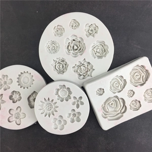 Détail de quatre moules en silicone blanc avec motifs de fleurs et de succulentes pour le DIY