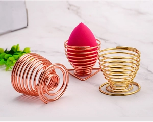 Rose gold and gold wire makeup sponge holders on a white marble surface