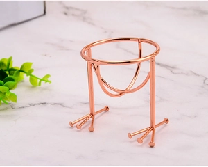Macro shot of rose gold metal makeup sponge holder with bird claw feet on marble surface