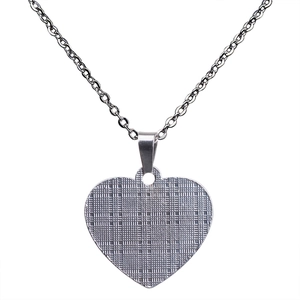 Detailed close-up of a silver heart pendant necklace with refined cross-hatch texture