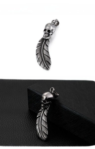 Detailed view of punk style skull and feather pendant with vintage engraved texture