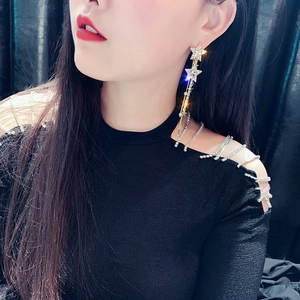 Close-up of star shaped rhinestone earrings with long hanging tassels on female model