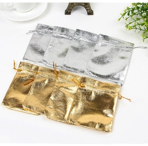 Macro shot of gold and silver drawstring gift bags with metallic textured fabric finish