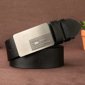 Detail of premium black leather belt featuring engraved metal buckle on leather backdrop