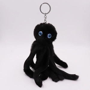 Close-up of black plush octopus keychain with soft fur, blue eyes and metal chain link