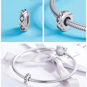 Macro detail of S925 silver charm with zircons and hollow crossover pattern on a bracelet