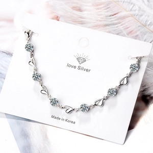 Elegantes Silberarmband mit hohlen Herzanhängern und runden Zirkonia auf weißer Karte