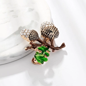 Sparkling crystal hazelnut brooch with green enamel leaf on elegant marble plate