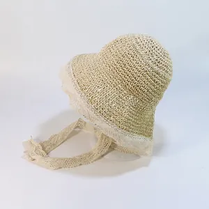 Détail du chapeau de paille beige avec bordure en dentelle blanche et rubans à nouer