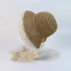 Gros plan sur un chapeau de paille orné d'une bordure en dentelle blanche et longs rubans