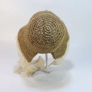 Détail d'un chapeau en paille fait main avec bordure en dentelle fleurie et rubans