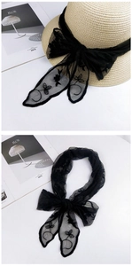 Detail showing black lace scarf with floral embroidery used as a decorative hat ribbon
