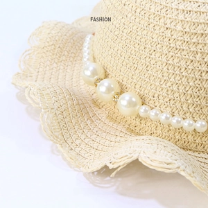 Detailed view of woven straw hat with wavy brim and elegant faux pearl decorative chain
