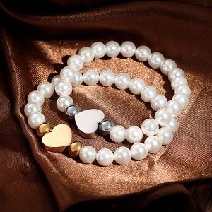 Two-piece shell pearl bracelet set with heart pendants on luxurious brown silk
