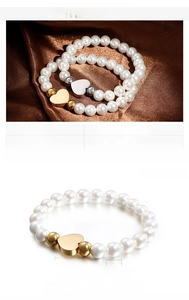 Detail of shell pearl bracelet with heart pendant in gold and steel finish