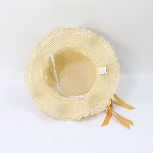 Detail view of woven straw hat featuring wavy lace edges and a bright yellow satin ribbon
