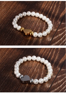Close-up of pearl bracelets with heart charms in gold and silver finishes on wood