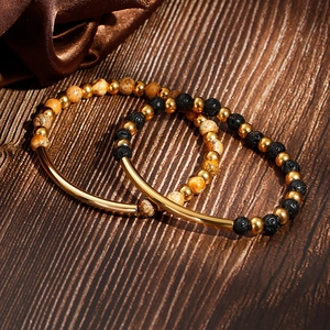 Elastic beaded bracelet with turquoise, lava stone, and gold metal tube on wood surface