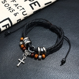 Men's punk braided leather bracelet with cross pendant and wooden beads on a dark background