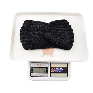 Close-up of black twisted knit headband on a digital scale showing 57.1g weight