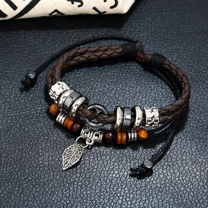 Detailed view of layered leather bracelet featuring vintage silver leaf charm and beads