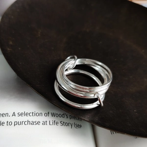Artistic close-up of multilayer silver nested rings on vintage ceramic and book page