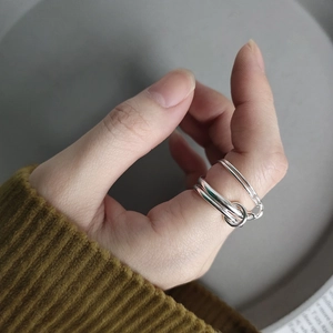 Close-up of interlocking triple band 925 sterling silver rings worn on a finger