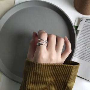 Detailed view of layered 925 sterling silver multi-line ring on finger in soft lighting