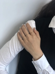 Detail of four minimalist thin gold stacking rings worn by a model in a close-up shot