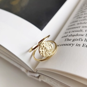 Minimalist gold coin ring in 925 sterling silver with vintage relief on a book