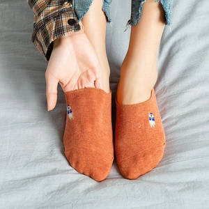 Orange cotton invisible socks with cute cartoon embroidery worn on gray background