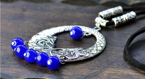 Detailed macro view of silver pendant with vibrant blue beads on black cord necklace