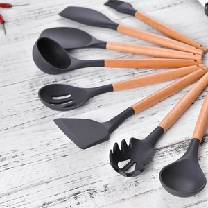 Dark grey silicone kitchen utensil set with wooden handles on white wood background