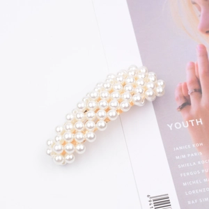 Detailed view of elegant pearl hair clips with gold base on a fashion magazine