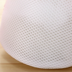 Macro shot of breathable honeycomb mesh fabric on a thick white padded laundry wash bag