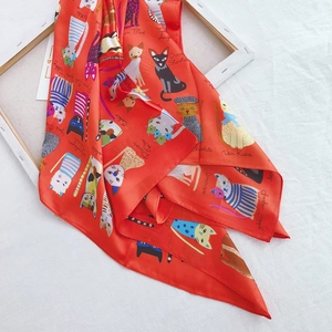 Detail of 90cm silk scarf featuring colorful cartoon cat patterns on a bright red base