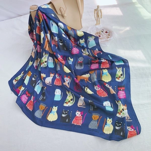 Detailed view of dark blue silk scarf with cat patterns tied on a handbag