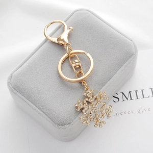 Golden snowflake keychain with sparkling crystals on a premium velvet jewelry display