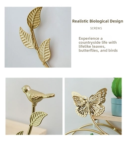 Macro detail of golden metal wall decor featuring leaf, bird and butterfly elements