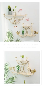 Detail of gold metal wall shelf with decorative birds and a light wood base board