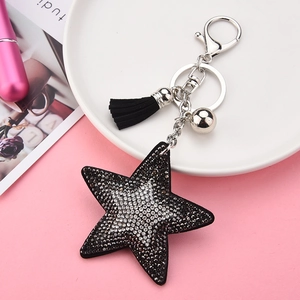 Détail du porte-clés étoile en strass avec pompon noir et accessoire cloche argentée